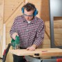 Mann mit blauem LUX Kapselgehörschutz beim Holzsägen für optimalen Gehörschutz.