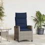 Grauer Poly Rattan Gartensessel mit marineblauen Kissen, verstellbar, neben passendem Beistelltisch.