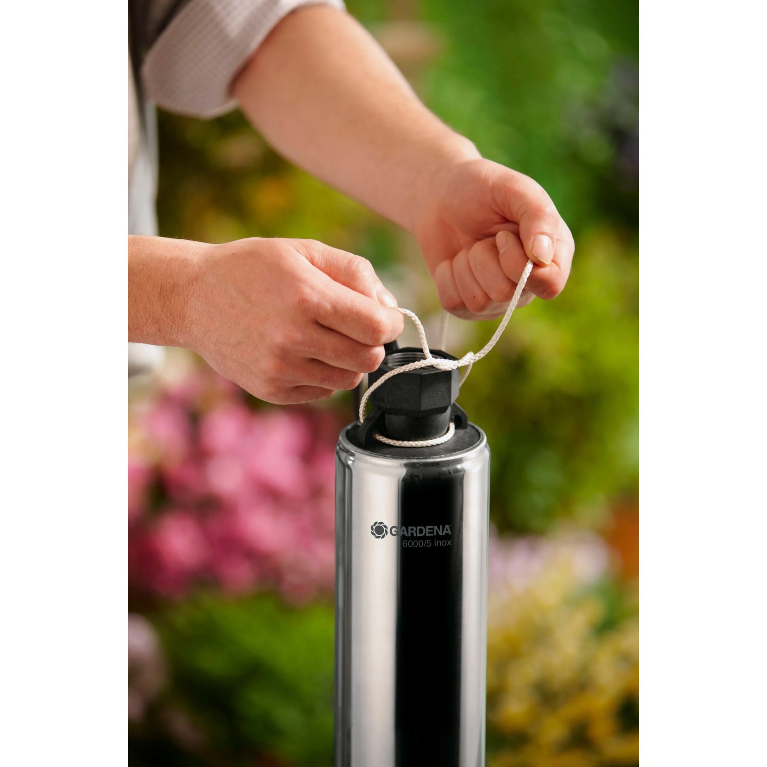 Gardena Premium Tiefbrunnenpumpe 6000/5 inox: Person befestigt Seil an Edelstahl-Pumpe.