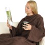 Frau mit brauner Bestlivings Kuscheldecke mit Ärmeln und Tasse auf dem Sofa.