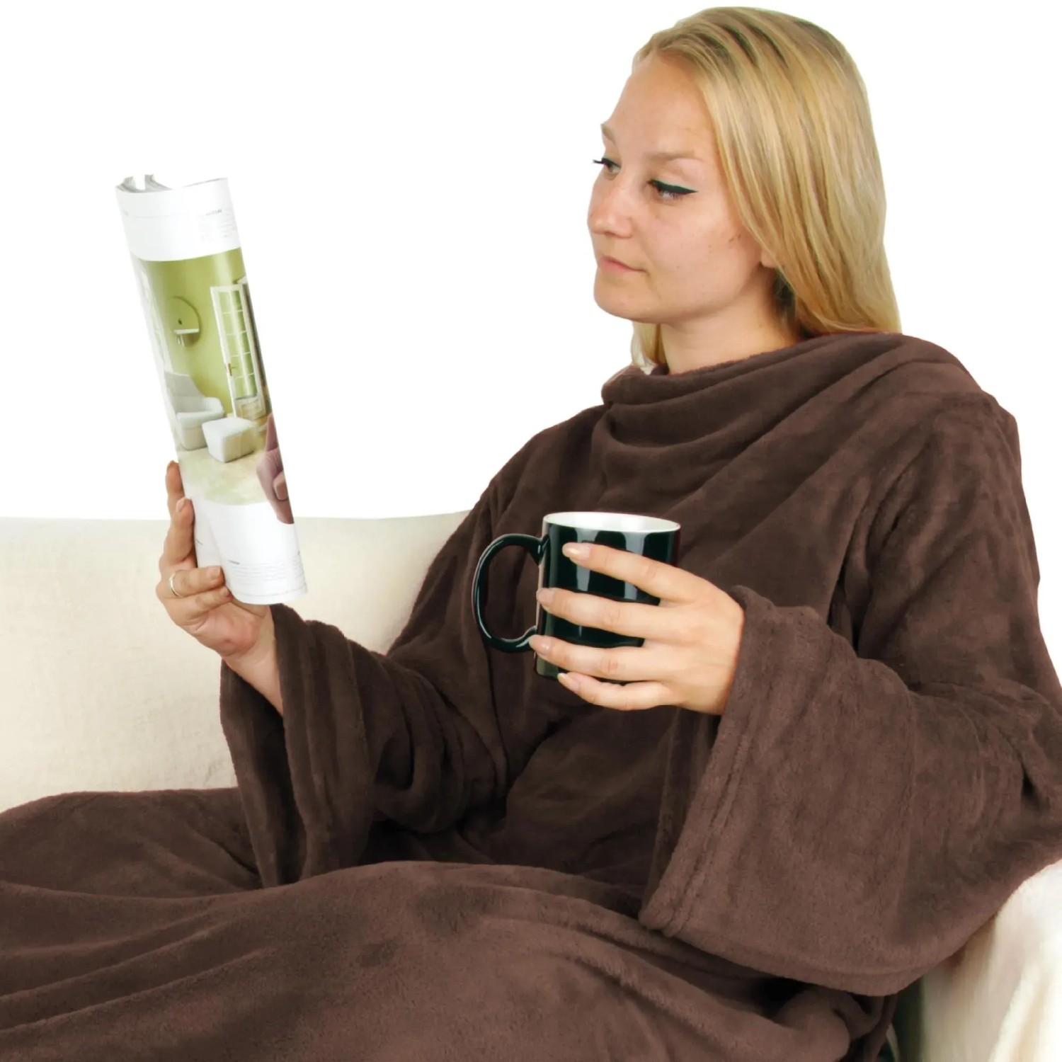 Frau mit brauner Bestlivings Kuscheldecke mit Ärmeln und Tasse auf dem Sofa.