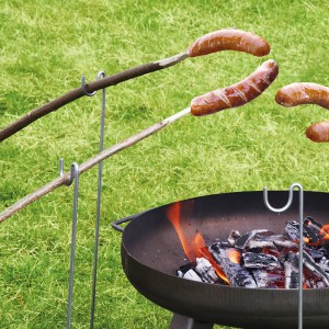 Bellissa Grillspießhalter aus verzinktem Stahl mit Würstchen über Lagerfeuer.