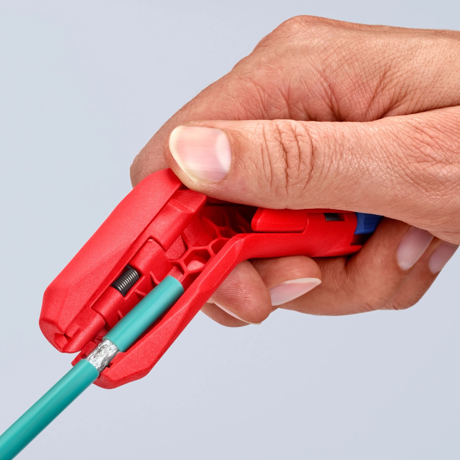 Hand nutzt Knipex ErgoStrip Zange zum Abmanteln eines Kabels. Universal-Abmantelungswerkzeug in Rot.