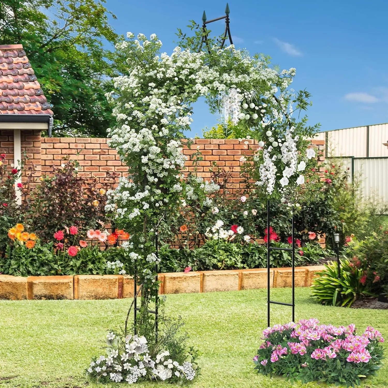 Schwarzer Costway Rosenbogen aus Metall, bewachsen mit weißen Blüten, im Garten.