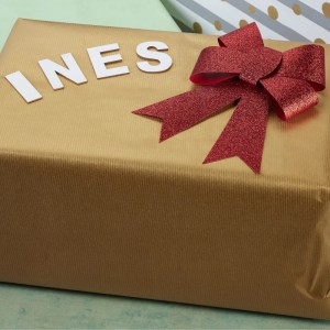 Geschenk mit roter Schleife und dem Namen "INES" aus weißen Relaxdays Holz Buchstaben.