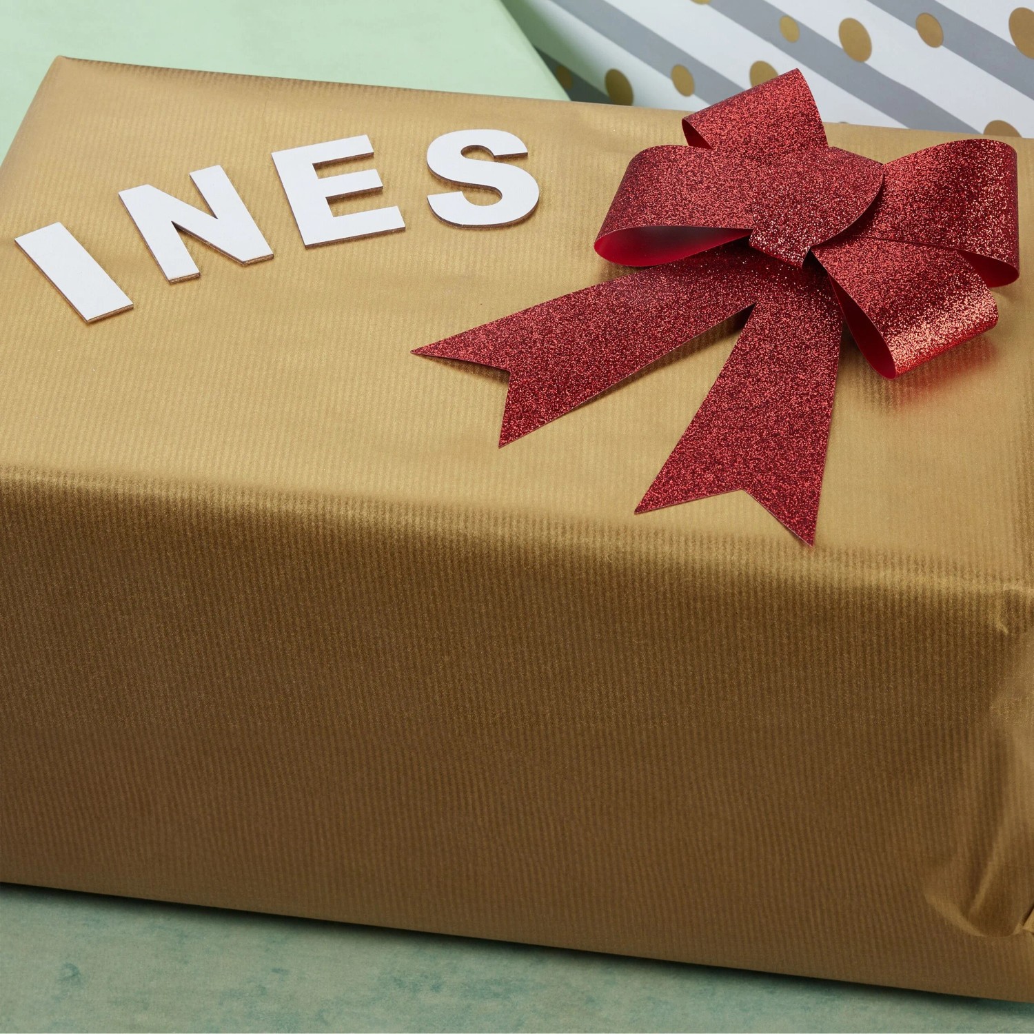 Geschenk mit roter Schleife und dem Namen "INES" aus weißen Relaxdays Holz Buchstaben.