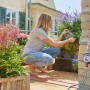 Gardena Bewässerungscomputer Flex am Wasserhahn mit Frau beim Gärtnern auf dem Balkon.