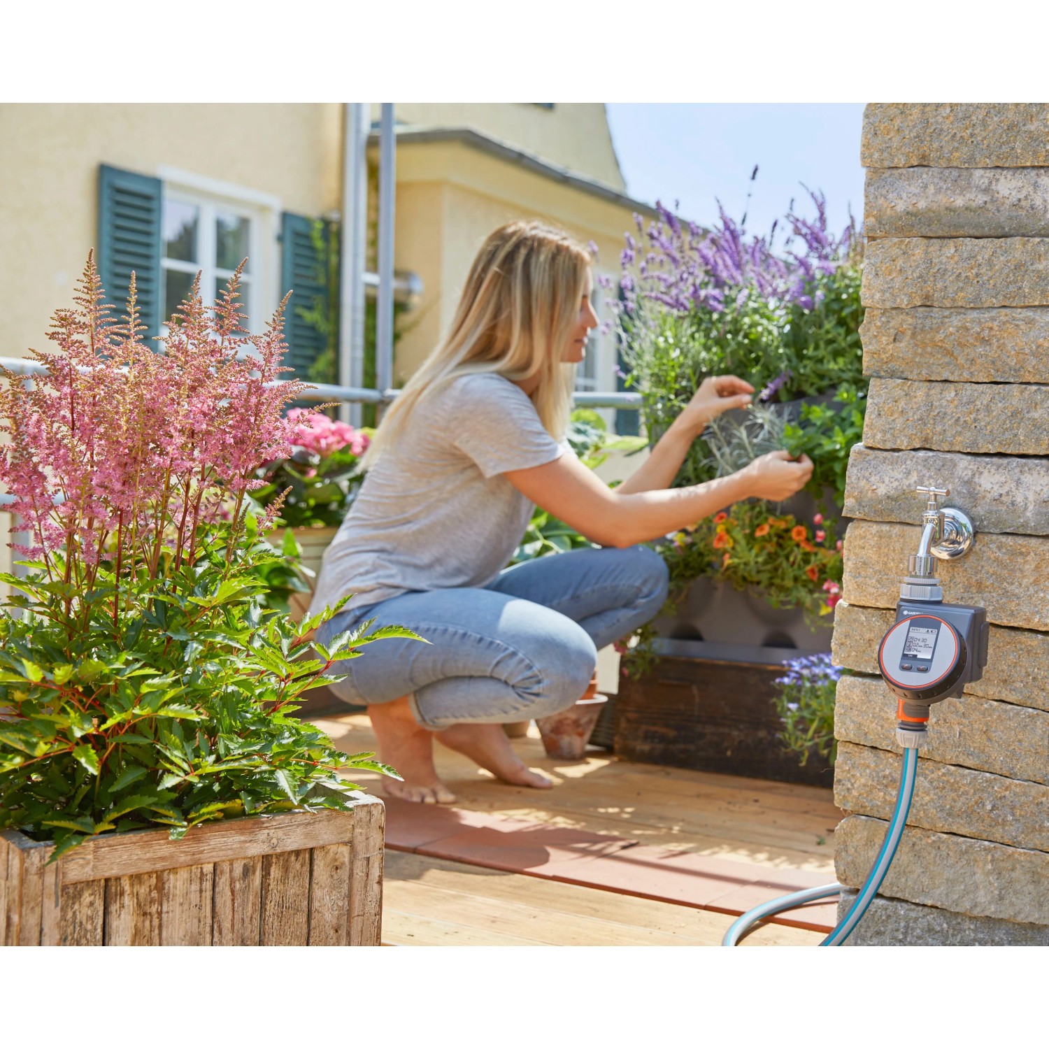 Gardena Bewässerungscomputer Flex am Wasserhahn mit Frau beim Gärtnern auf dem Balkon.