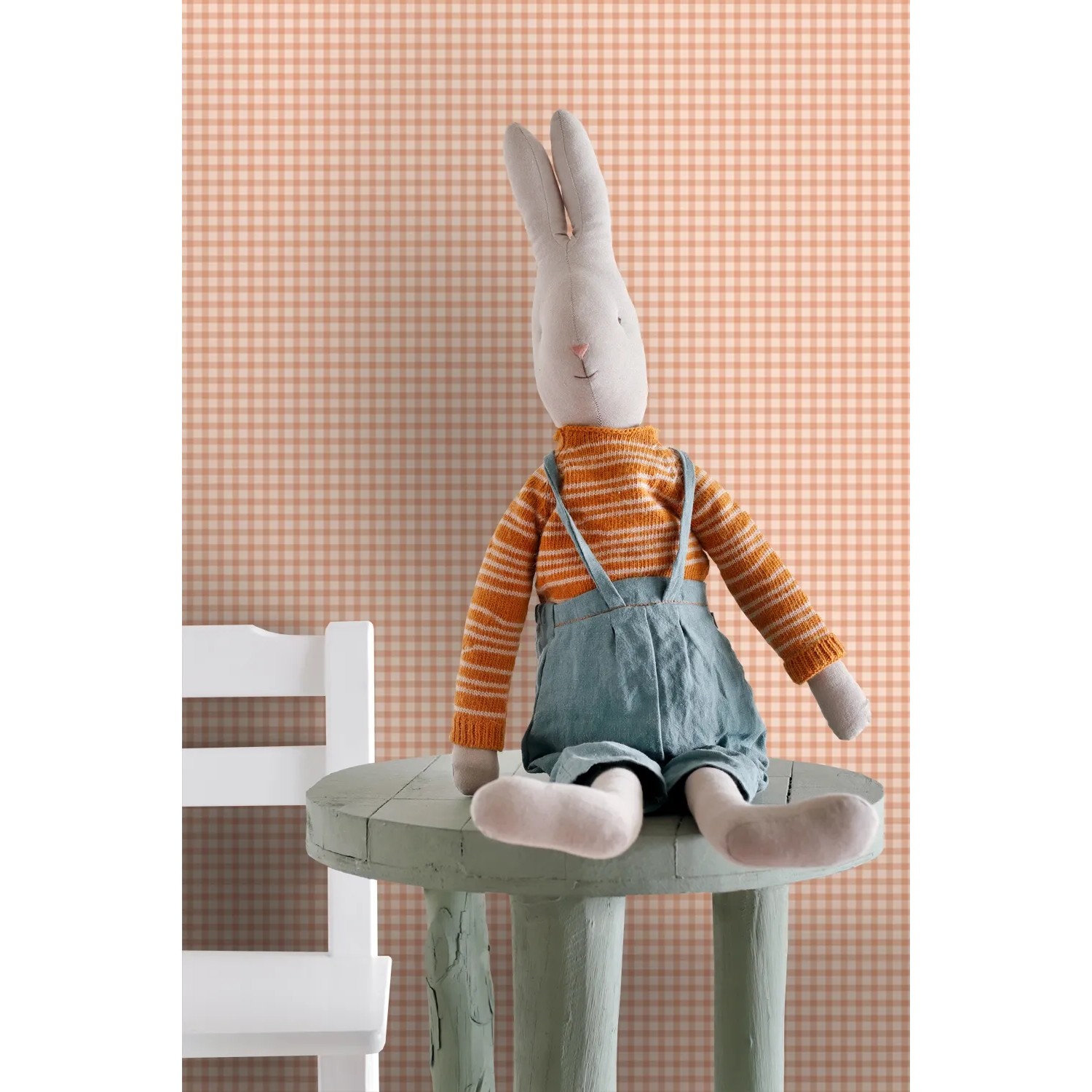 ESTAhome Vliestapete mit orangefarbenem Karomuster an einer Wand, davor ein Stoffhase auf einem Tisch. Dekorative Tapete.