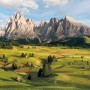 Komar Vlies Fototapete Alpen: Berglandschaft mit grünen Wiesen und markanten Gipfeln.