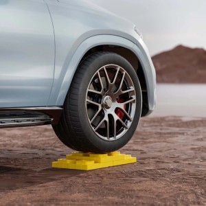 Rad eines Wohnwagens steht auf gelben Unterlegplatten / Auffahrkeilen.