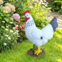 Dekorative Gartenfigur Henne aus Polyresin, weiß mit rotem Kamm und gelbem Schnabel, im grünen Garten.