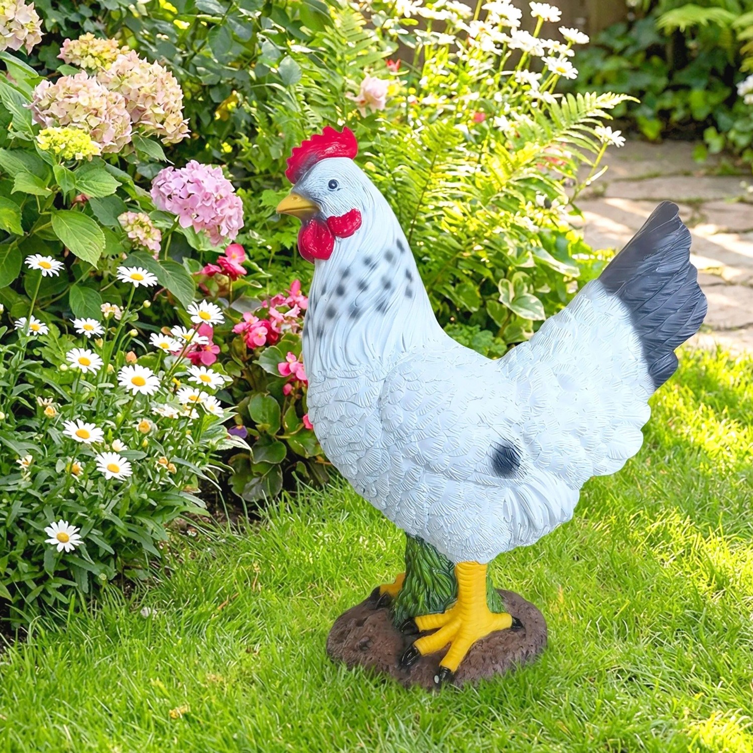Dekorative Gartenfigur Henne aus Polyresin, weiß mit rotem Kamm und gelbem Schnabel, im grünen Garten.