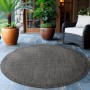 Runder, schwarzer Ayyildiz Outdoor-Teppich Giza (120x120cm) in Sisal-Optik auf einer Terrasse.