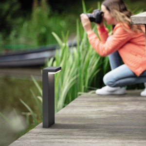 Anthrazitfarbene Philips LED Sockelleuchte Bustan (3.8 W) im Garten, fotografiert von einer Frau.