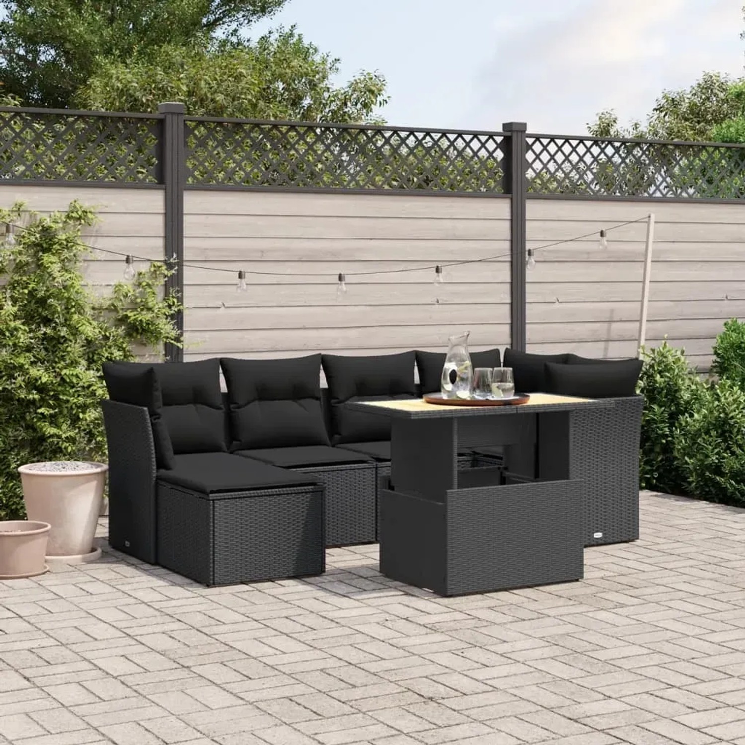 Schwarze 7-teilige Garten-Sofagarnitur aus Polyrattan mit Tisch und Kissen.