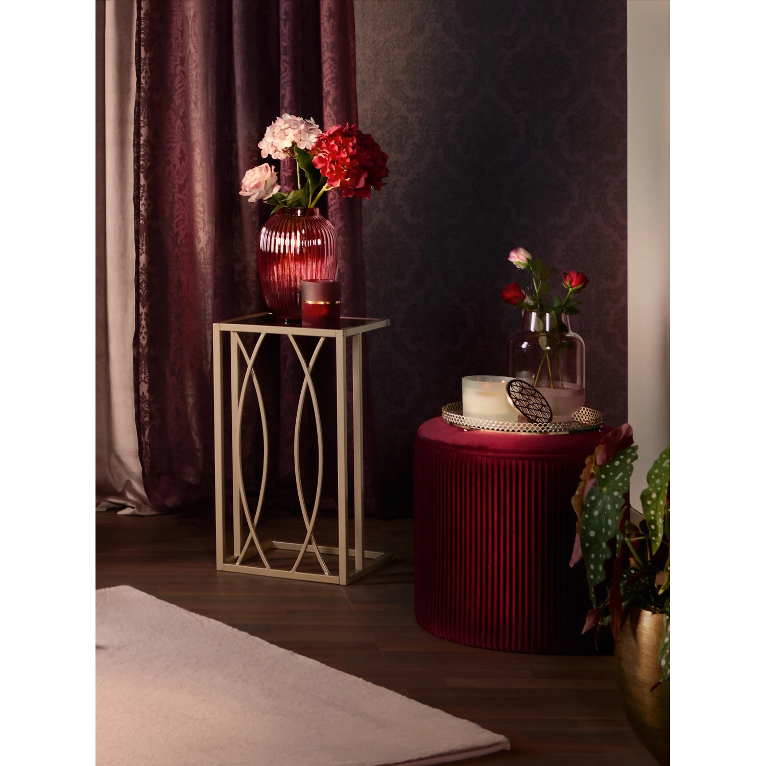 Eckiger Beistelltisch Blush Bordeaux mit goldfarbenem Gestell und Deko.