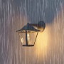 Schwarze Philips Outdoor-Wandleuchte Juli im Laternen-Design bei Regen.