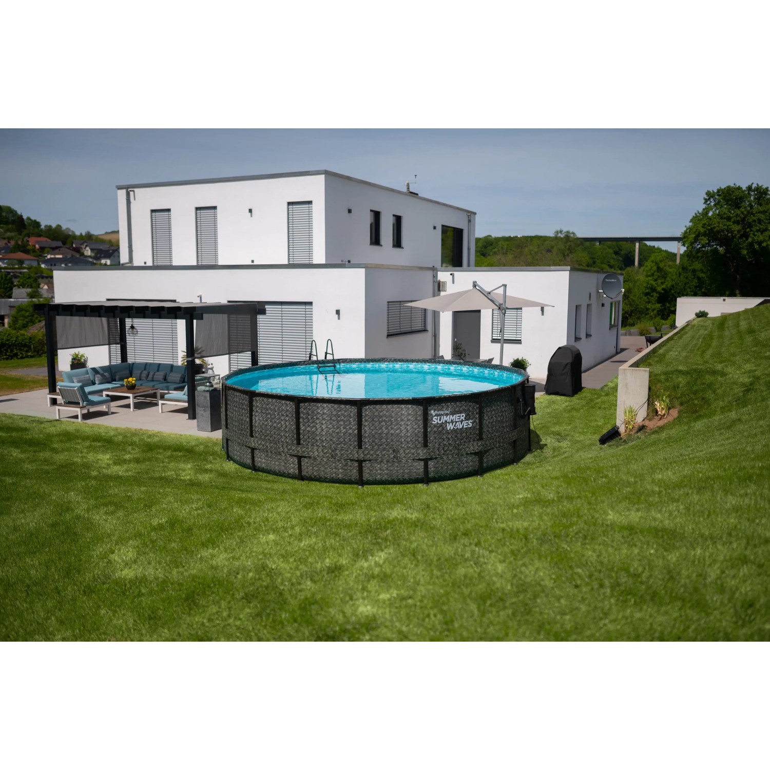 Runder Summer Waves Pool (549x132cm) in Rattangrau im Garten vor modernem Haus.