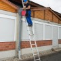Krause Schiebeleiter Stabilo, 2-teilig, im Einsatz an einem Haus zur Reinigung einer Dachrinne.