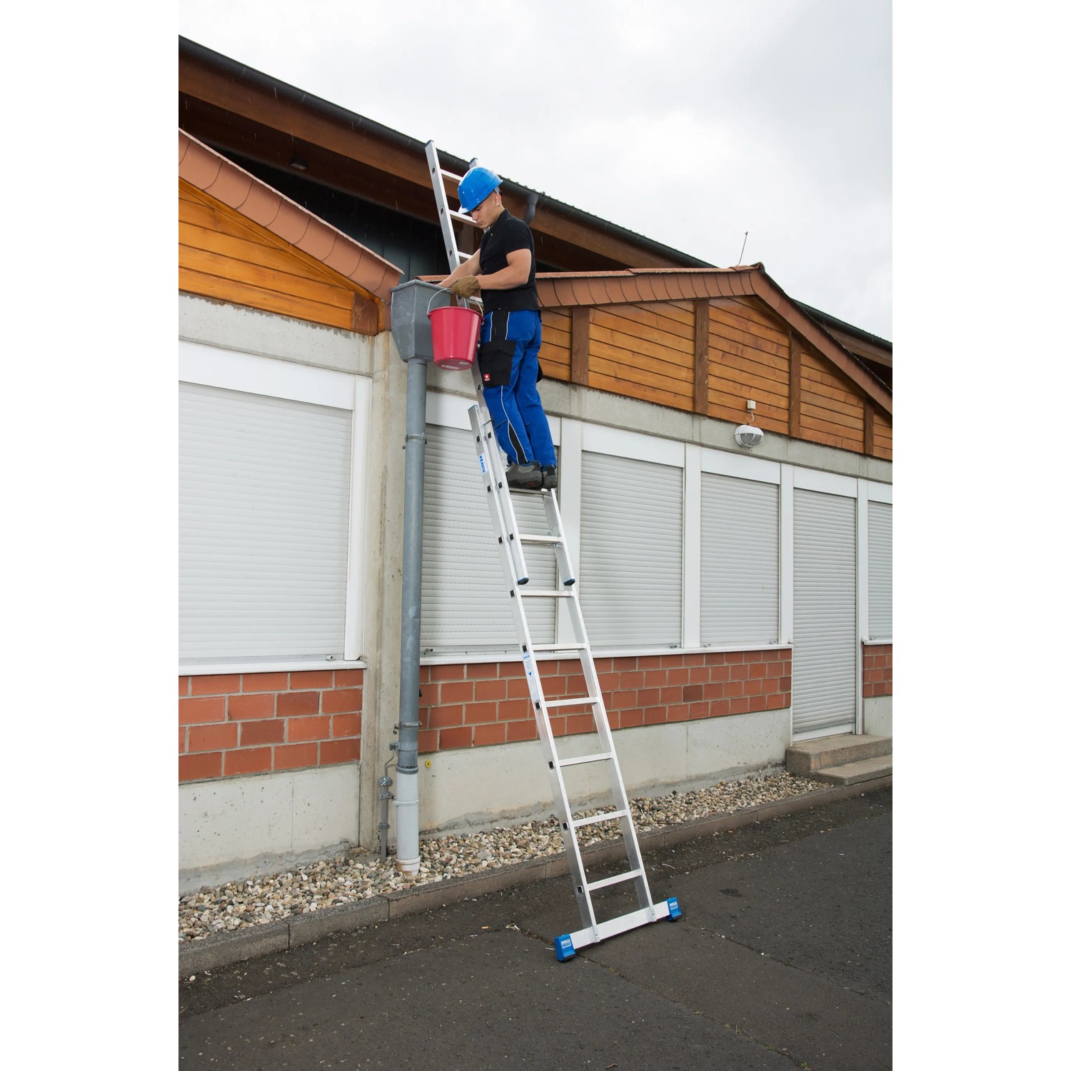Krause Schiebeleiter Stabilo, 2-teilig, im Einsatz an einem Haus zur Reinigung einer Dachrinne.