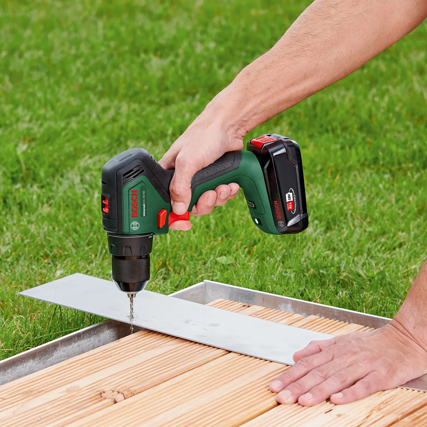 Bosch Akku-Bohrschrauber UniversalDrill 18V-60 beim Bohren in Metall auf Holzterrasse.