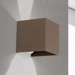 Quadratische LED Außenwandleuchte in Corten an Wand, mit warmweißem Lichtstrahl nach oben und unten.
