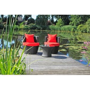 Schwarzes DELUKE Bistro-Set CARINA mit roten Kissen am See. Gartenmöbel-Set aus Kunststoffgeflecht.