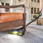 Ryobi Akku-Staubsauger Advanced 18V mit LED-Düse und Wandstation im Einsatz unter einem Sessel.