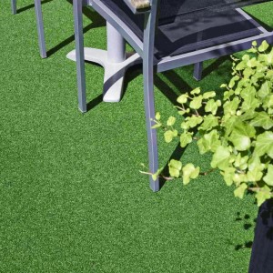 Grüner Primaflor Kunstrasen Summer B1 unter einem Tisch, ideal für Events und Messen.