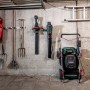 Metabo Akku-Rasenmäher RM 36-18 LTX BL 46 mit 2 Akkus und Ladegerät vor einer Betonwand.