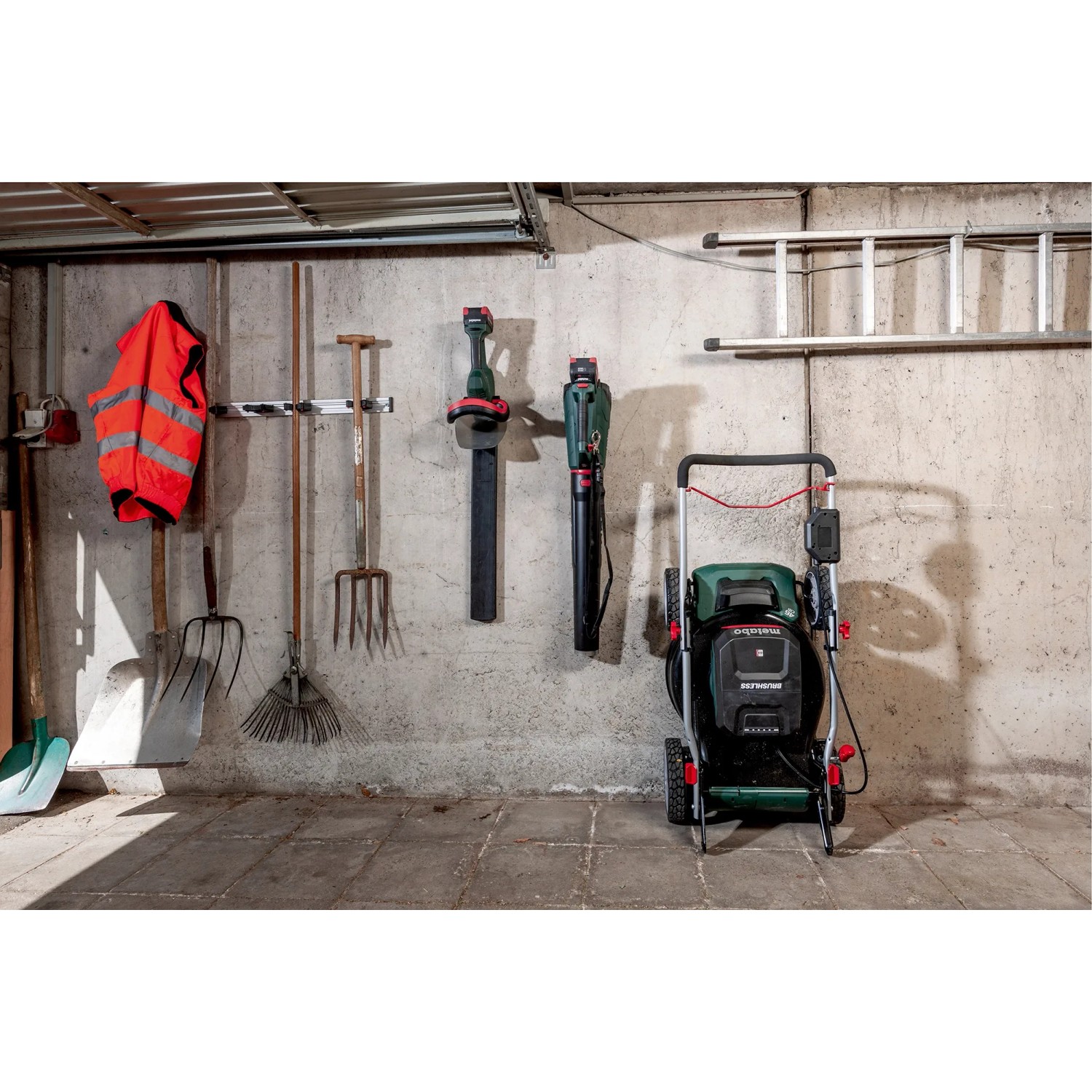 Metabo Akku-Rasenmäher RM 36-18 LTX BL 46 mit 2 Akkus und Ladegerät vor einer Betonwand.