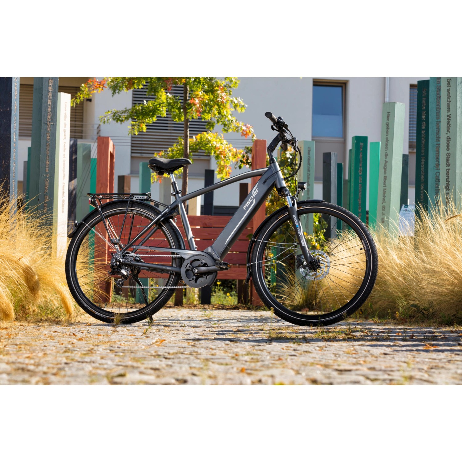 Graues Fischer E-Bike Viator 5.0i mit Diamantrahmen und Mittelmotor vor Gebäude.