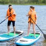Zwei Personen auf X4-Life Stand Up Paddle Boards mit Paddel und Schwimmweste auf dem Wasser.