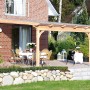 Skan Holz Terrassenüberdachung Ravenna aus hellem Douglasienholz mit transparentem Polycarbonatdach an Ziegelhaus.