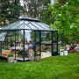 Juliana Gewächshaus Grand Oase 13 Anthrazit im Garten, mit Familie am Tisch. Begehbares Gewächshaus mit Aluminiumrahmen.