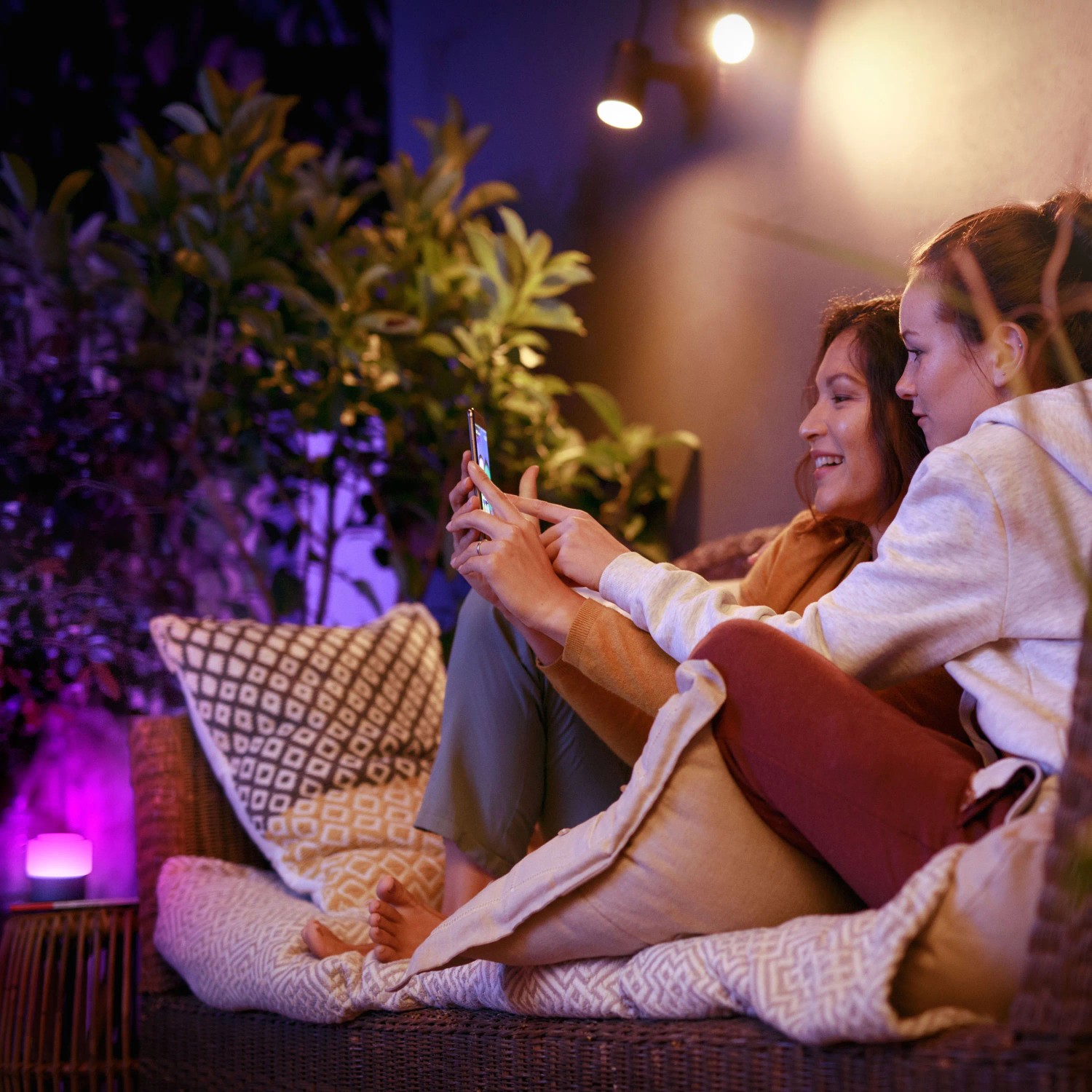 Zwei Frauen nutzen Philips Hue Lily LED-Spot im Garten, gesteuert per Smartphone.