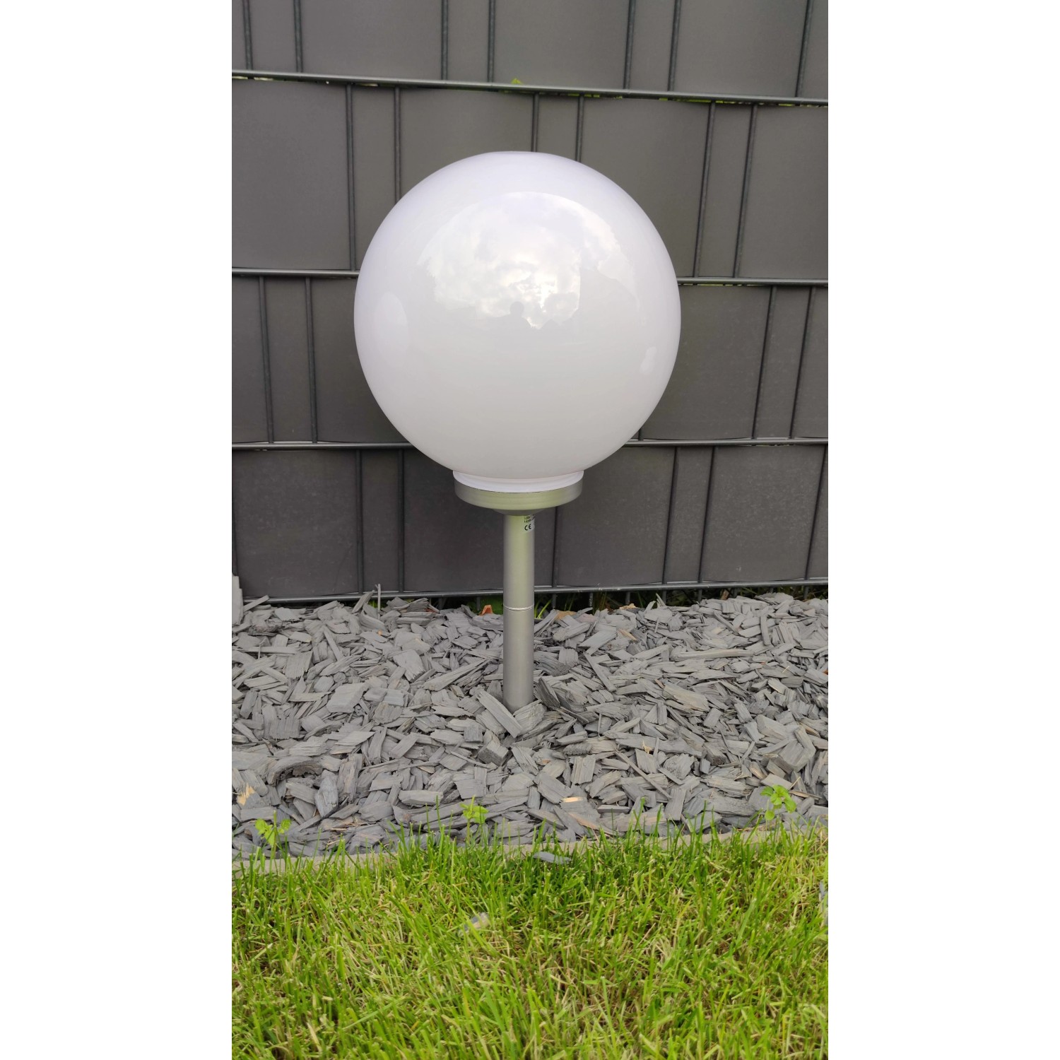 Dapo Solar Kugelleuchte Ola 25cm mit Erdspieß, weiße Kugel auf schwarzem Erdspieß im Garten.