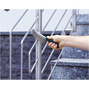 Hand mit Drahtbürste reinigt Metallgeländer. Wolfcraft Drahtbürsten Set, 3-teilig.