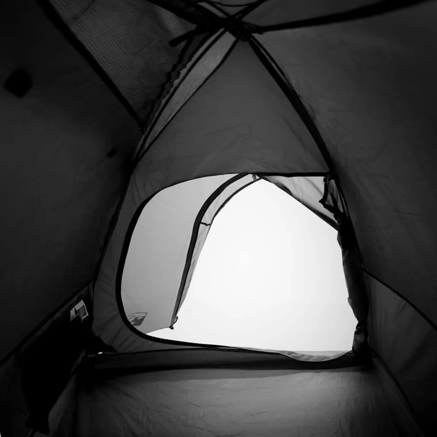 Blick aus einem dunklen Furnicato Kuppelzelt mit offener Tür ins helle Freie. Zeigt Verdunkelungsfunktion des Campingzelts.