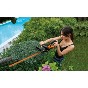 Frau schneidet Hecke mit Worx Akku-Heckenschere 20V WG260E.5 im Garten.
