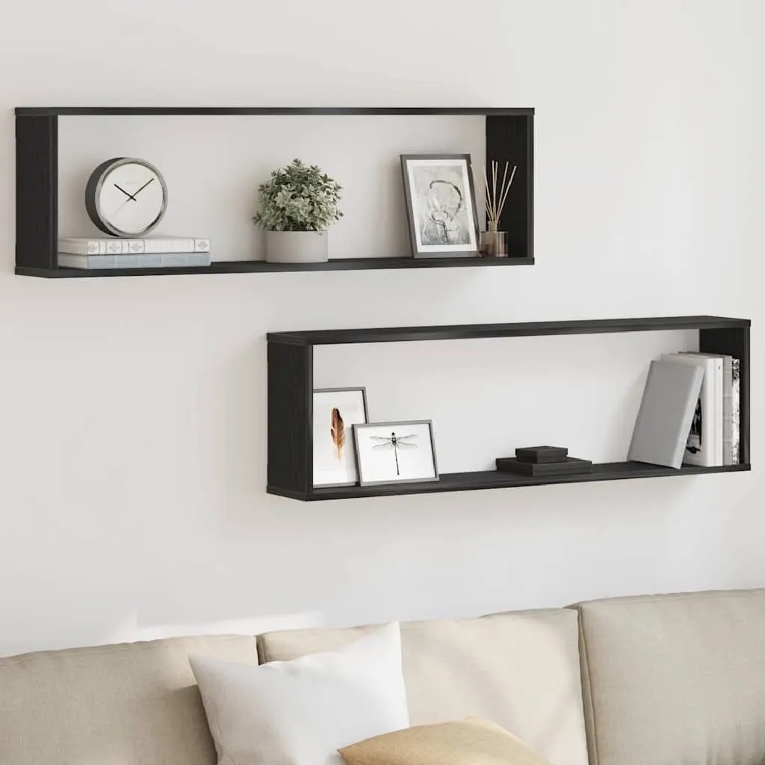 Zwei schwarze Würfelregale in Eichen-Optik an einer weißen Wand über einem Sofa dekoriert.