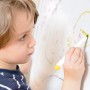 Kind malt mit Stift auf Whiteboard, erstellt mit Rust-Oleum Little Stars Weißtafelkit Winter Wunderland.