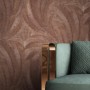 Newroom Vliestapete Savina Bronze mit Palmenmuster und Struktur neben einem Sessel.