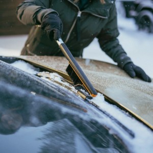 Frau benutzt Fiskars Auto-Schneebürste & Eiskratzer, um Schnee von einer Windschutzscheibe zu entfernen.