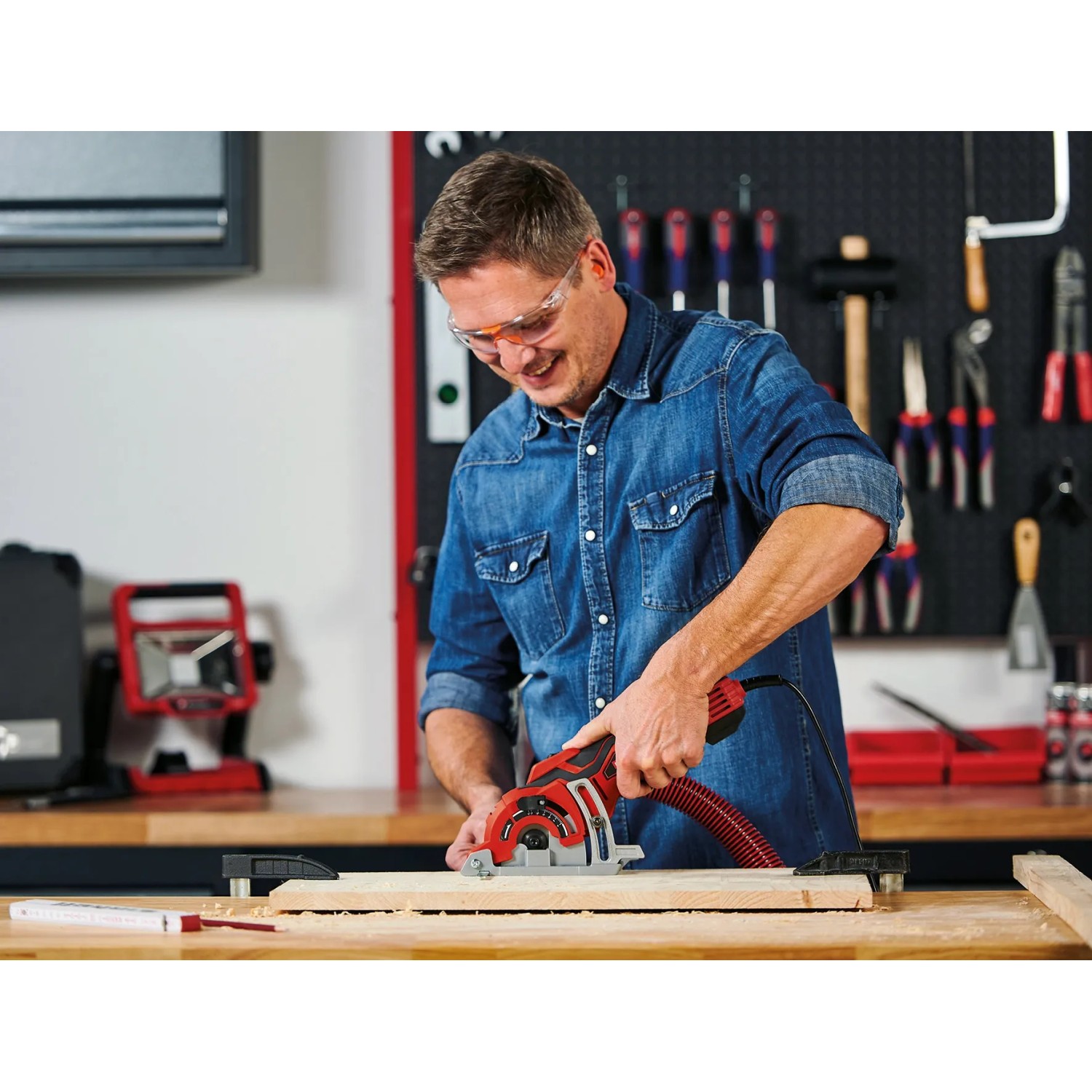 Ein Mann sägt Holz mit der Einhell Mini-Handkreissäge TC-CS 89 in der Werkstatt.