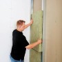 Mann montiert Rockwool Sonorock Trennwandplatte (40mm) aus Steinwolle in eine Wand.