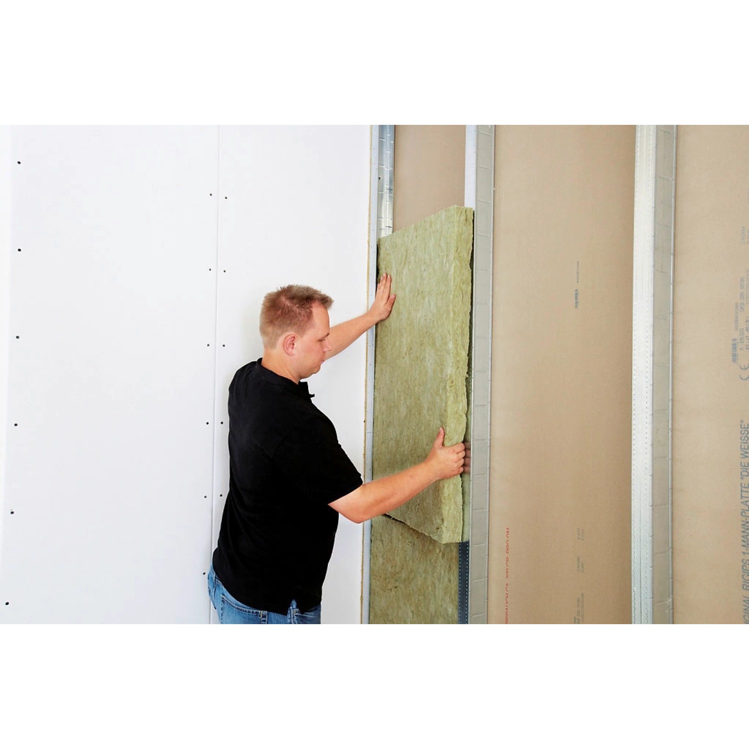 Mann montiert Rockwool Sonorock Trennwandplatte (40mm) aus Steinwolle in eine Wand.