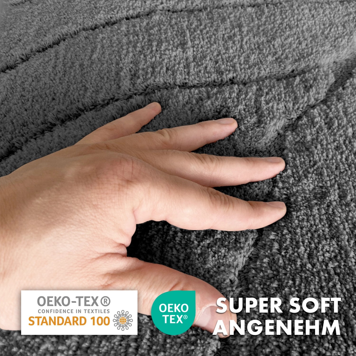 Detailaufnahme: Dunkelgraue Karat Badematte Maris mit Blattstruktur und Hand, die die weiche Oberfläche berührt.