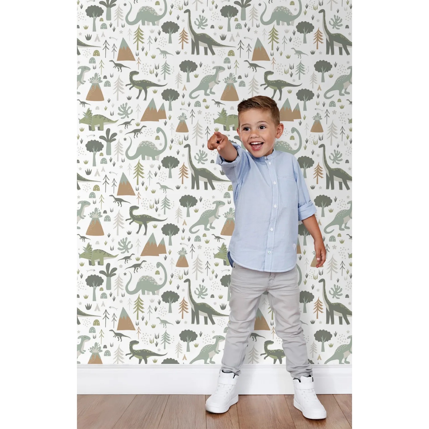 Fröhlicher Junge vor ESTAhome Vliestapete mit Vintage Dinosauriern, Bäumen und Bergen in Blau/Grün für Kinderzimmer.